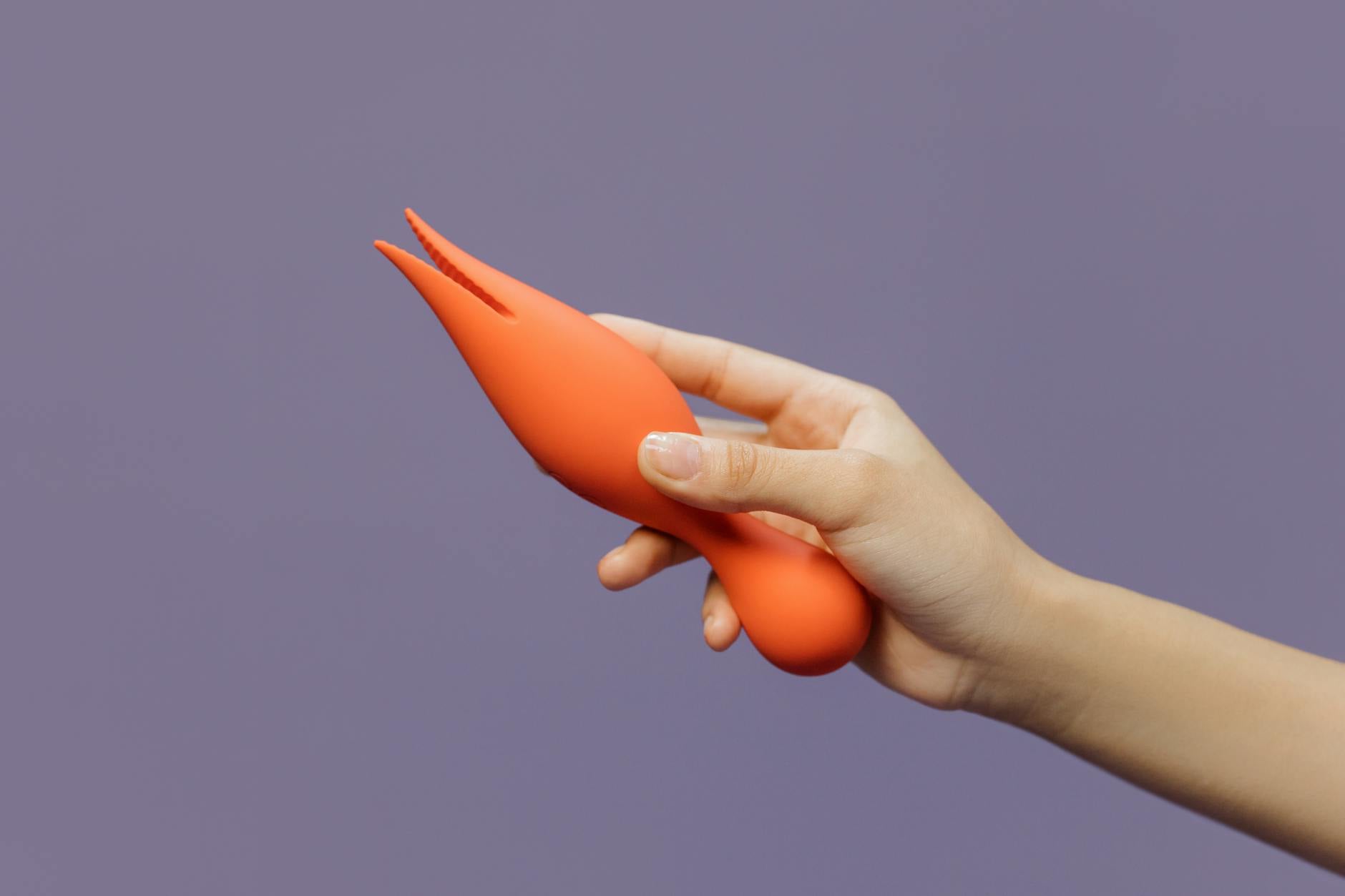 Hand holding a citrus-colored vibrator against a minimalistic backdrop, symbolizing modern sexual confidence